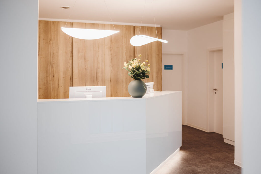 Empfangstresen mit Blumenvase und Pendelleuchten in der Zahnarztpraxis Leff & Mitew in Borsdorf bei Leipzig